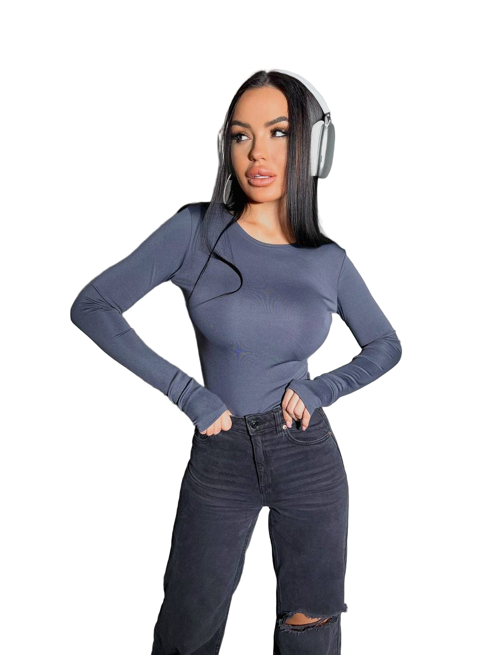 Woman wearing a blue long-sleeve top and black jeans with headphones on a white background