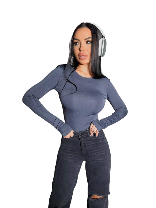 Woman wearing a blue long-sleeve top and black jeans with headphones on a white background