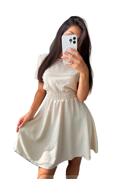Woman wearing a white dress taking a mirror selfie on a plain background