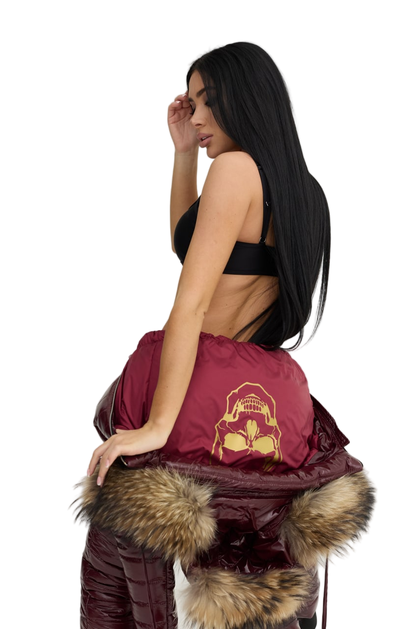 Woman holding a maroon bag with fur trim against a white background