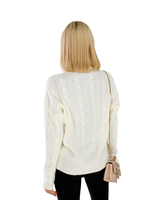 Woman wearing a white cable knit sweater with a beige handbag on a white background