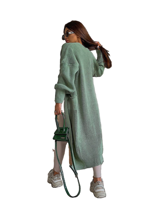 Woman wearing a long green cardigan holding a green handbag on a white background