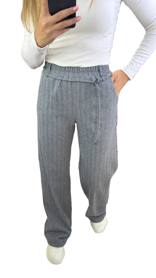 Person wearing gray checkered pants with a white top on a white background