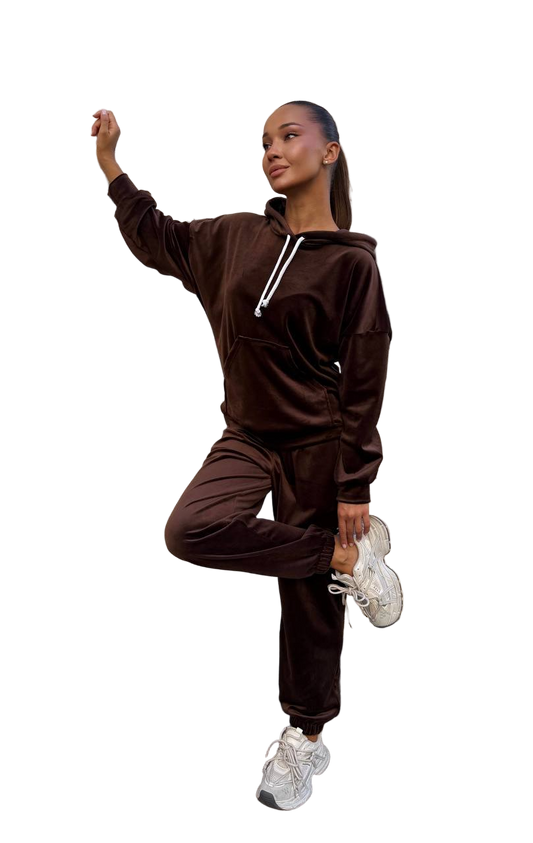 Person wearing a brown tracksuit with white sneakers on a white background