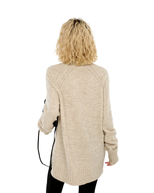 Person wearing a beige cardigan on a white background