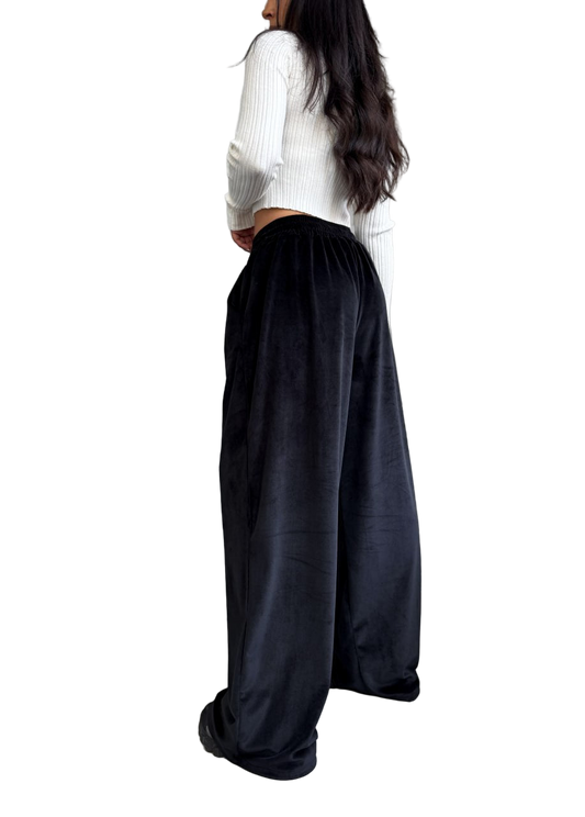 Person wearing a white top and black wide-leg pants on a white background