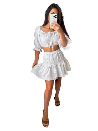 Woman taking a mirror selfie wearing a white outfit on a white background