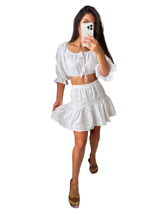 Woman taking a mirror selfie wearing a white outfit on a white background