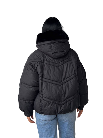 Person wearing a black puffer jacket with a hood on a white background
