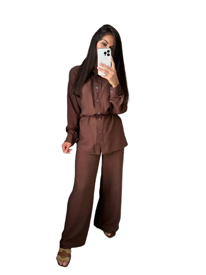 Person wearing a brown outfit holding a phone on a white background