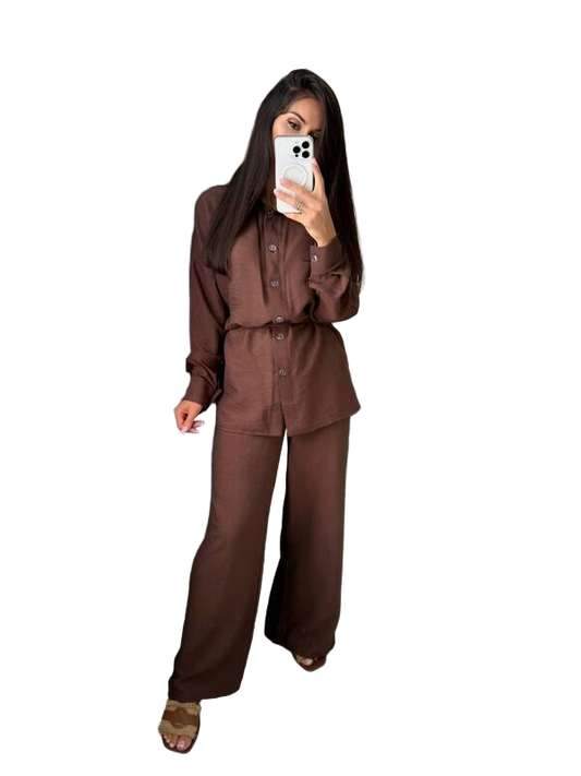 Person wearing a brown outfit holding a phone on a white background