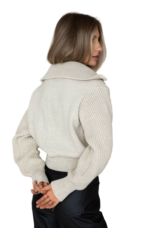 Woman wearing a beige knitted sweater over a white background