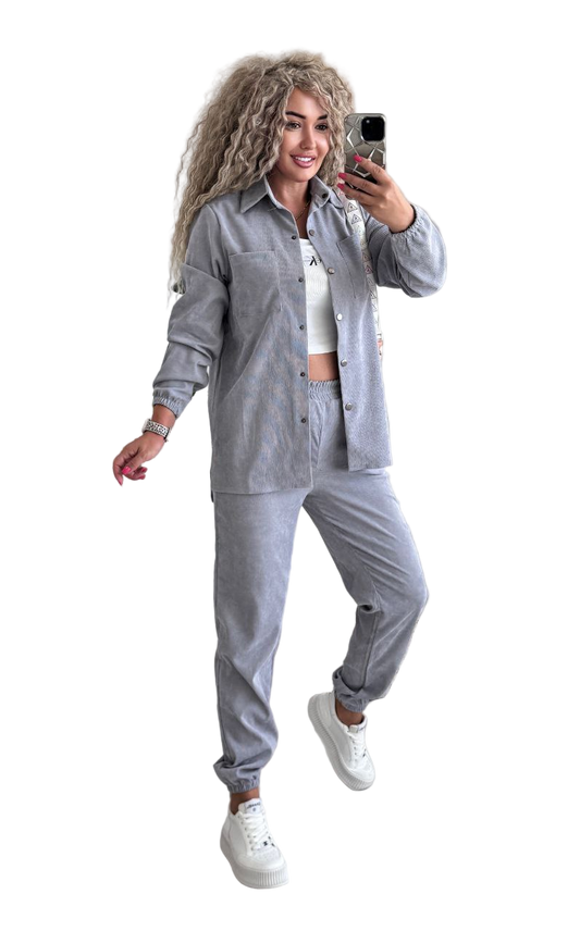 Woman in gray tracksuit taking a selfie on a white background