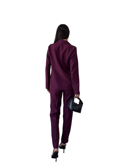 Person wearing a purple suit holding a black handbag on a white background