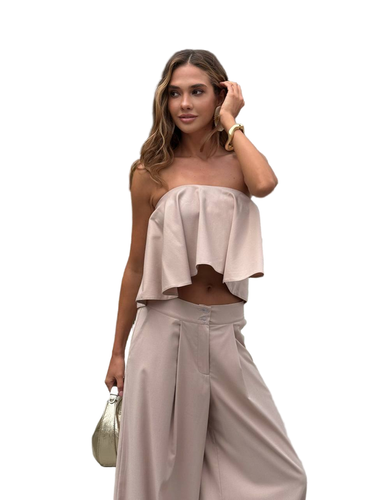 Woman wearing a beige strapless top and wide-leg pants on a white background