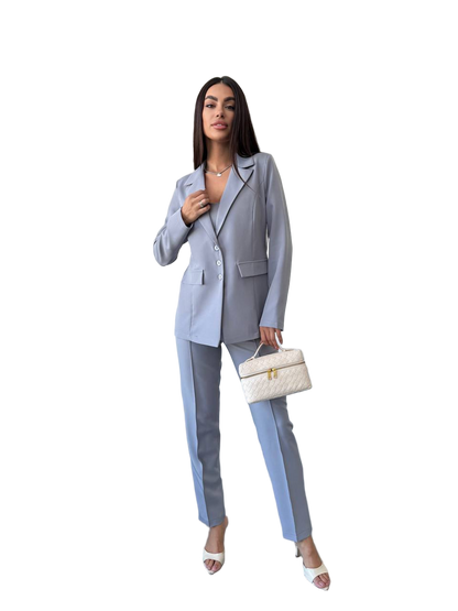 Woman wearing a light blue suit holding a white handbag on a white background