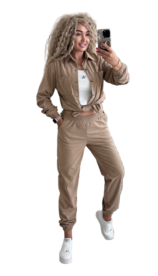 Woman in beige tracksuit taking a selfie on a white background