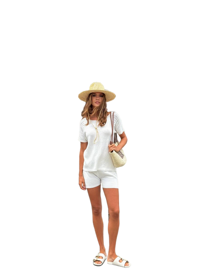 Woman in a white outfit with a hat and sandals on a white background