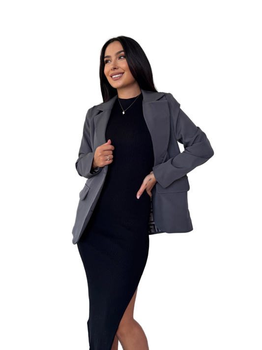 Woman wearing a gray blazer over a black dress on a white background