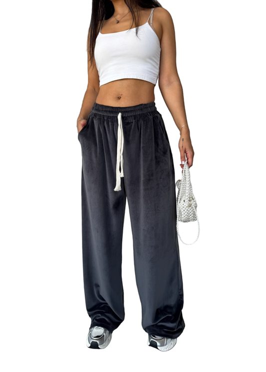 Woman wearing a white crop top and dark gray sweatpants on a white background