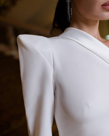 Close-up of a person wearing a white long-sleeve top with a blurred background
