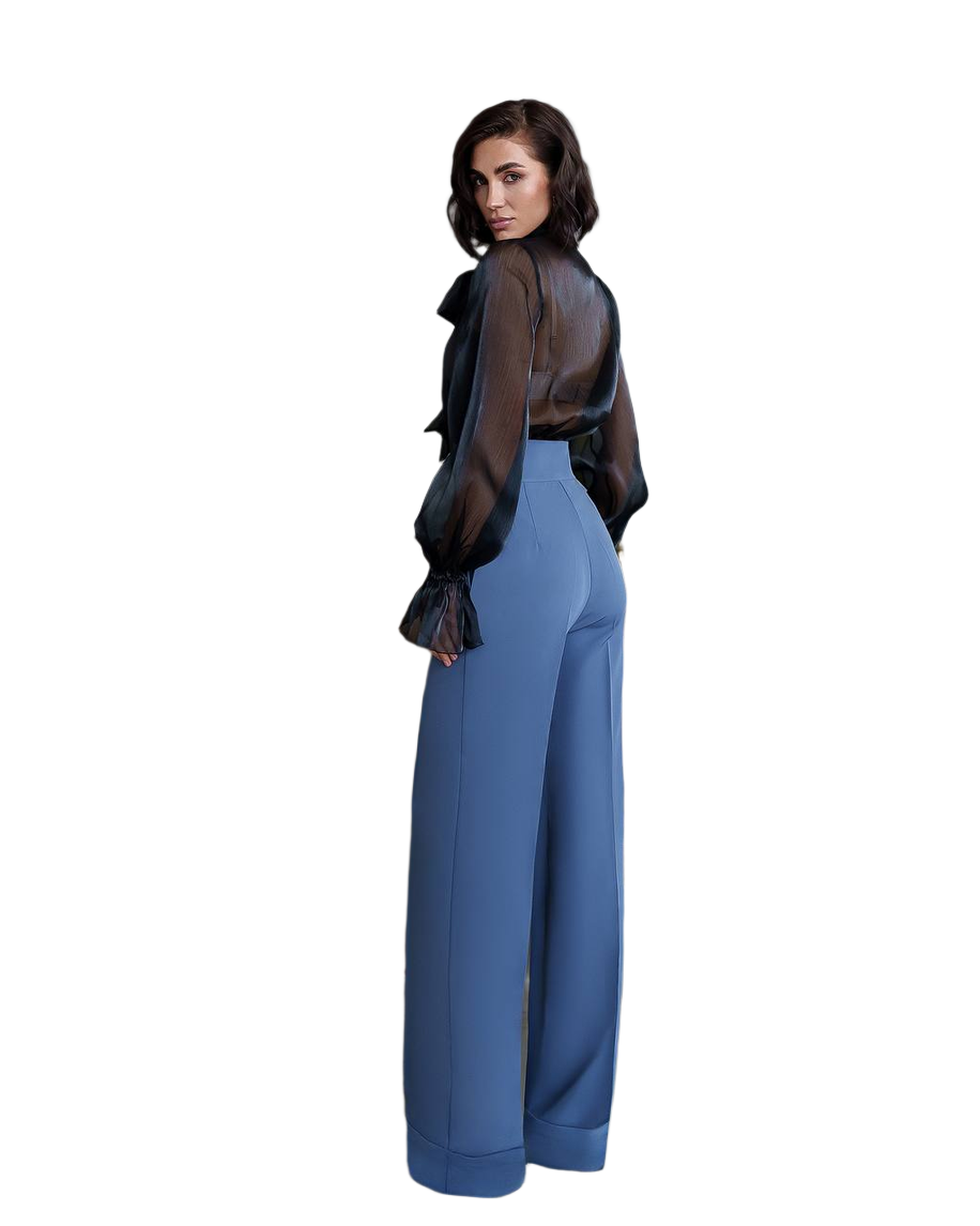 Woman wearing a black sheer top and blue pants on a white background