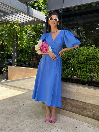 Woman in a blue dress holding flowers outdoors