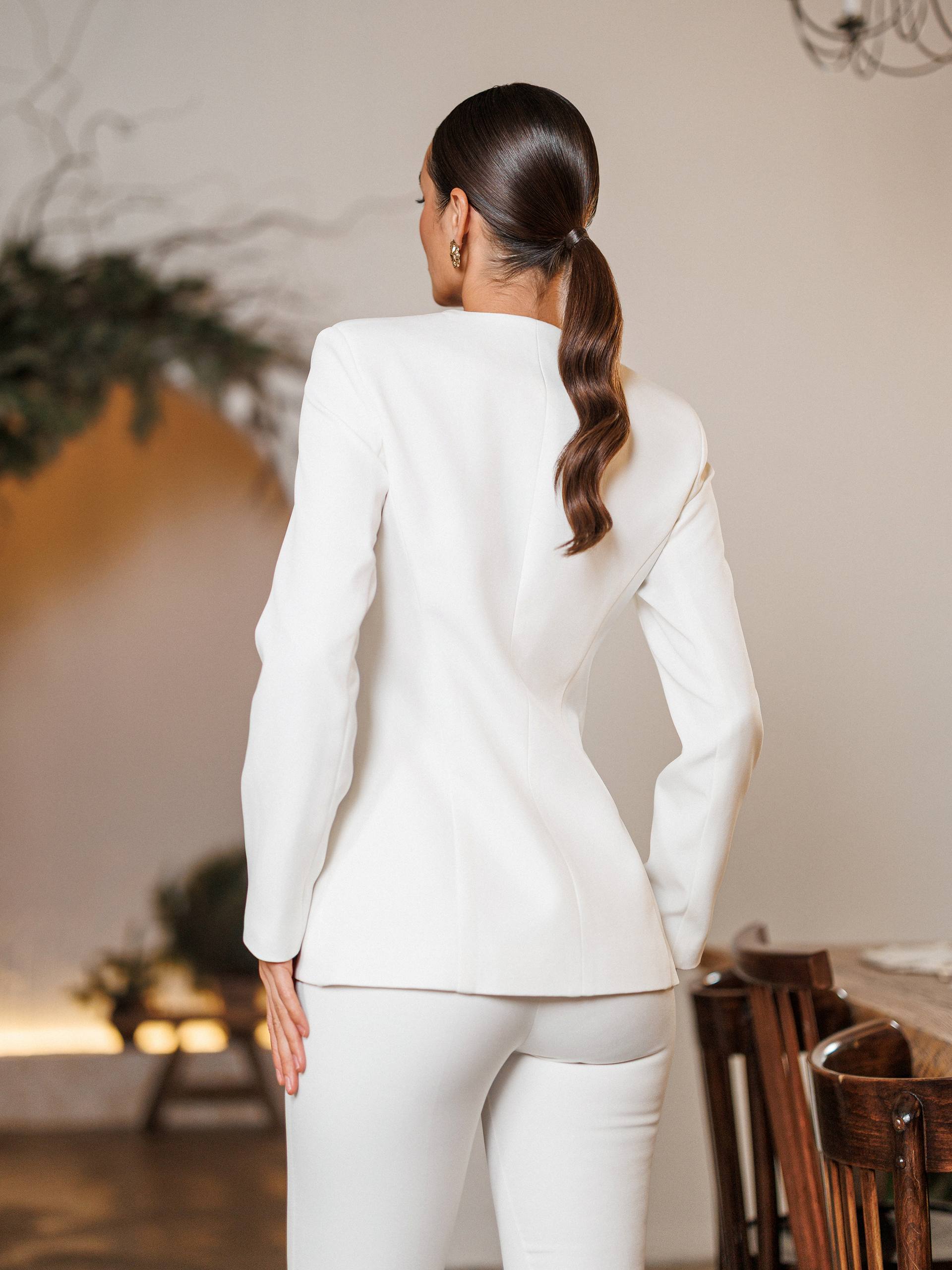 Person wearing a white suit in an indoor setting with blurred background