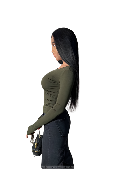 Woman wearing a green long-sleeve top and dark pants on a white background