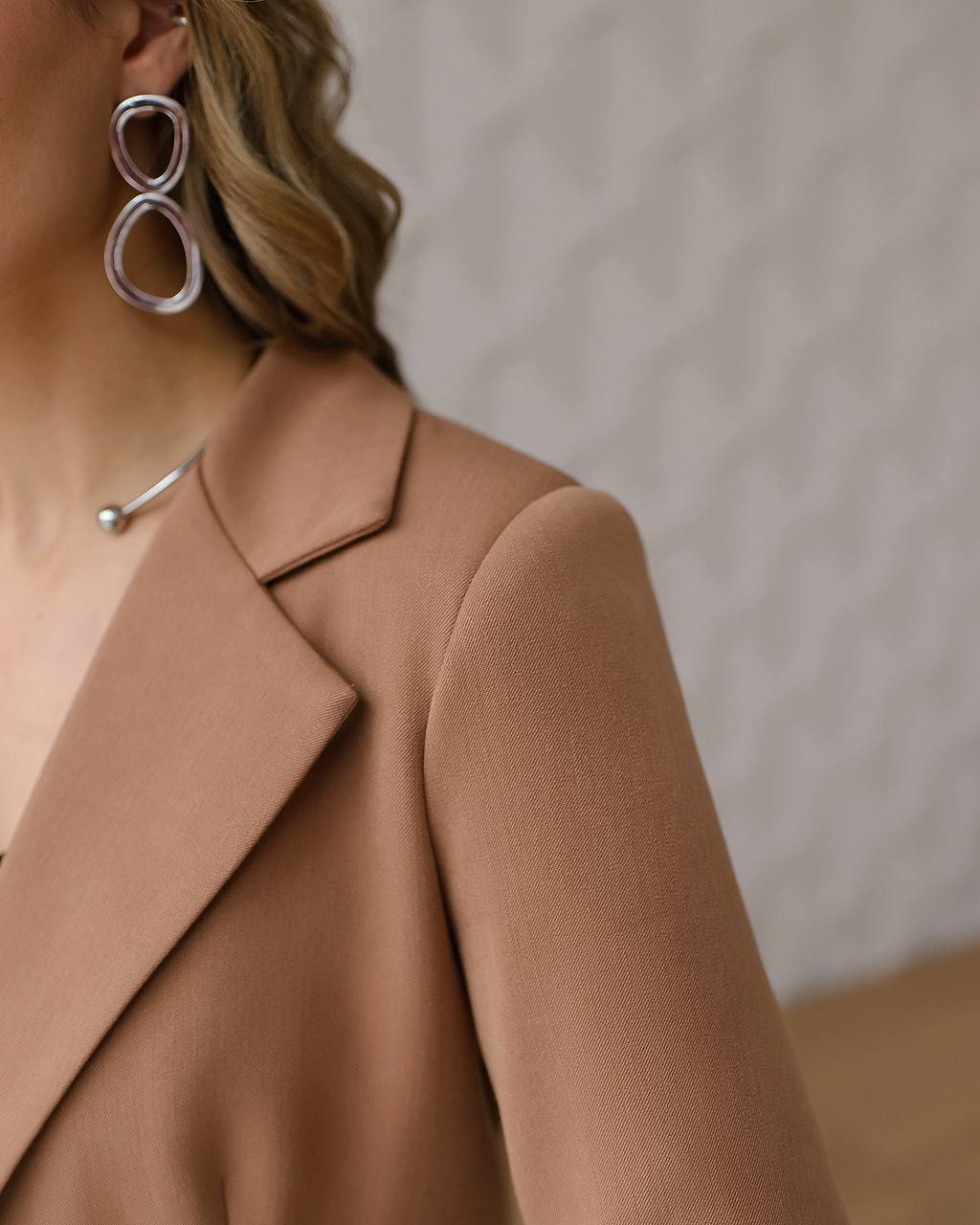 Close-up of a person wearing a brown coat with a neutral background