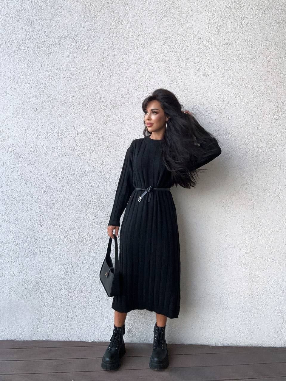 Woman wearing a black dress against a white wall