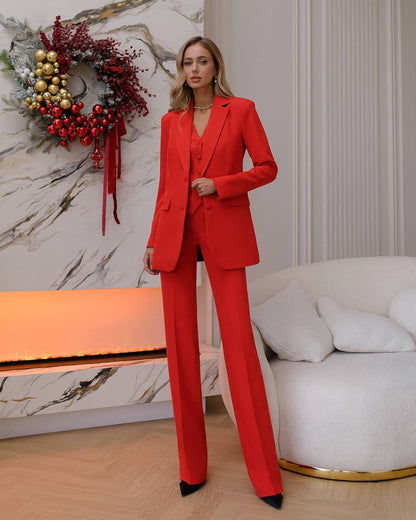 Person wearing a red suit standing in a stylish room with decorative elements.