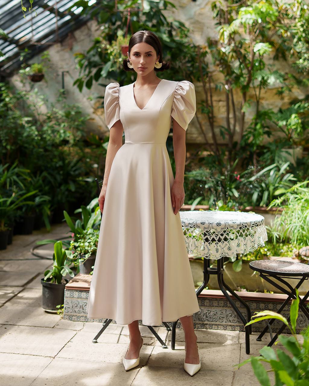 Woman in a beige dress standing in a garden setting