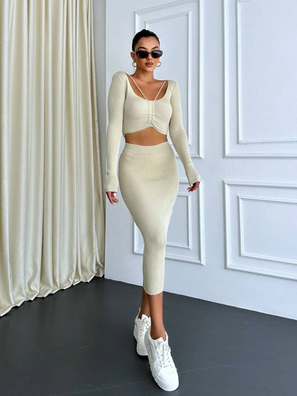Person wearing a cream-colored outfit with white sneakers in a room with white walls and curtains.