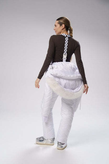 Person wearing a white outfit with suspenders on a gray background