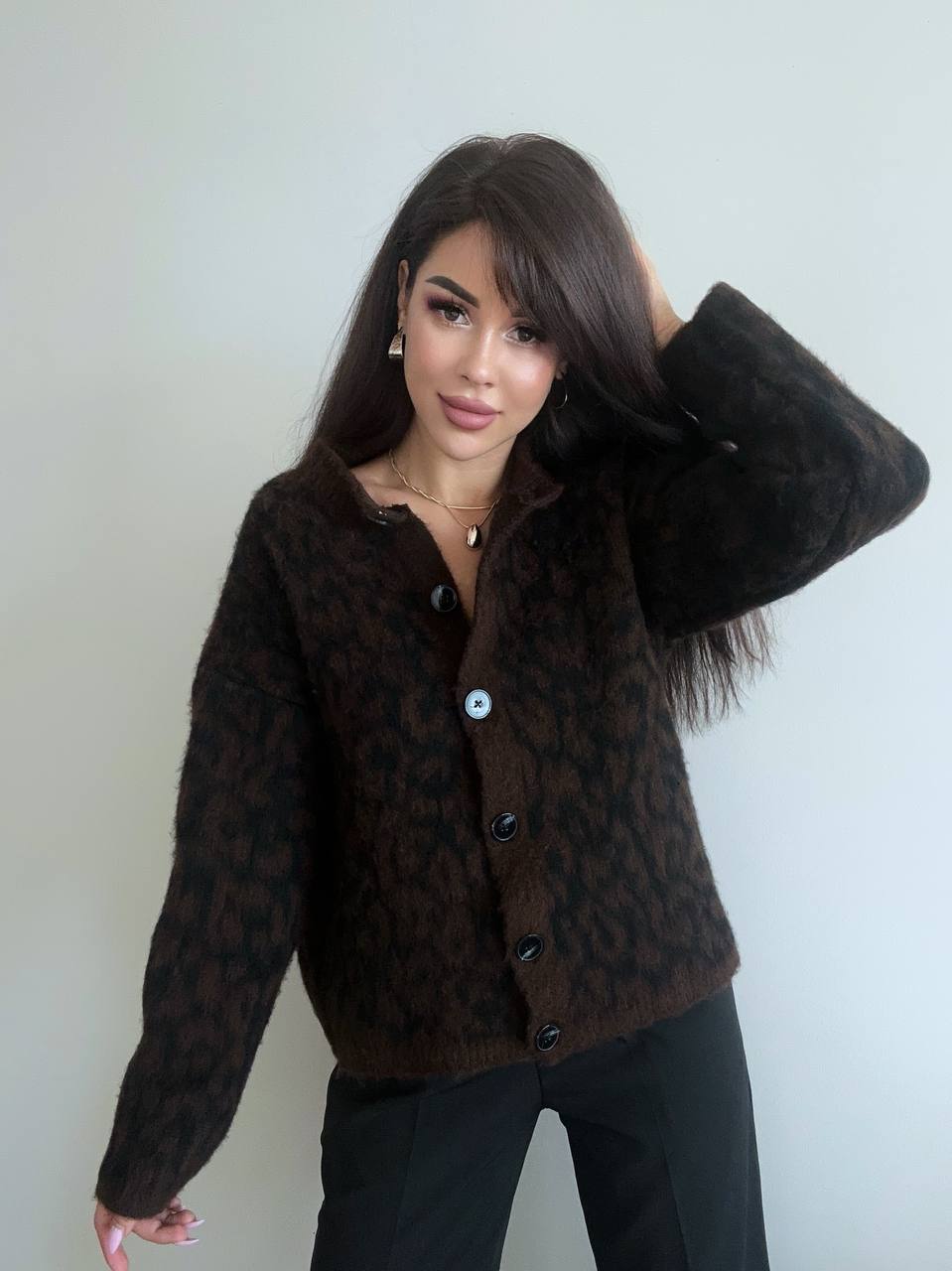 Woman wearing a brown patterned jacket against a plain background