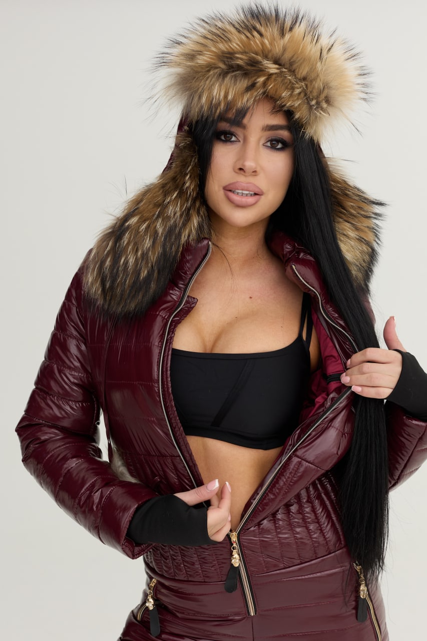 Woman wearing a burgundy leather jacket with fur hood on a white background