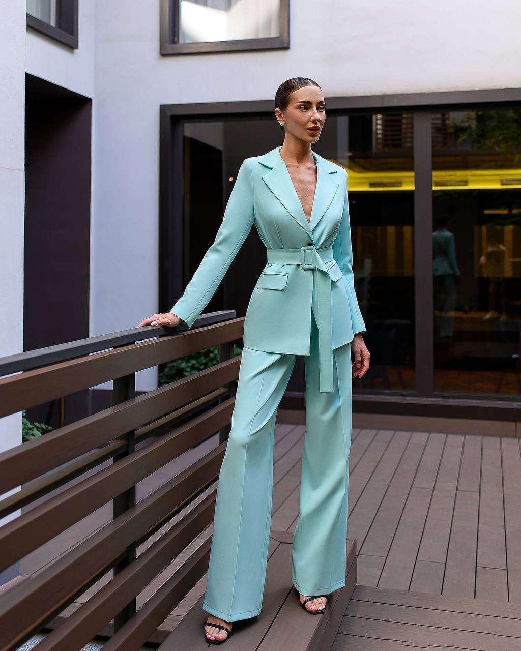 Woman in a light blue suit standing on a wooden deck.