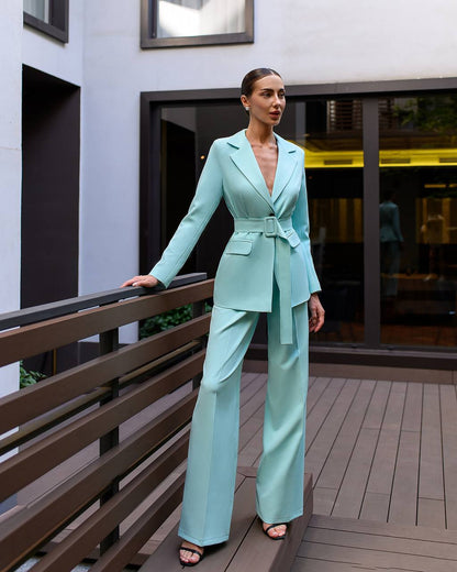 Woman in a light blue suit standing on a wooden deck.