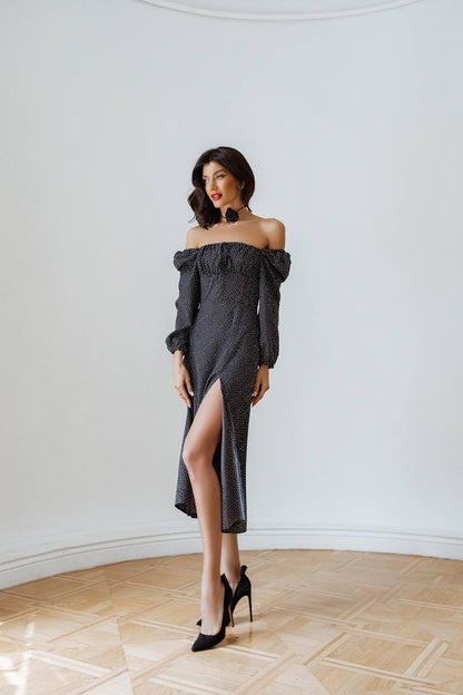 Woman wearing a dark gray off-shoulder dress with a high slit on a white background