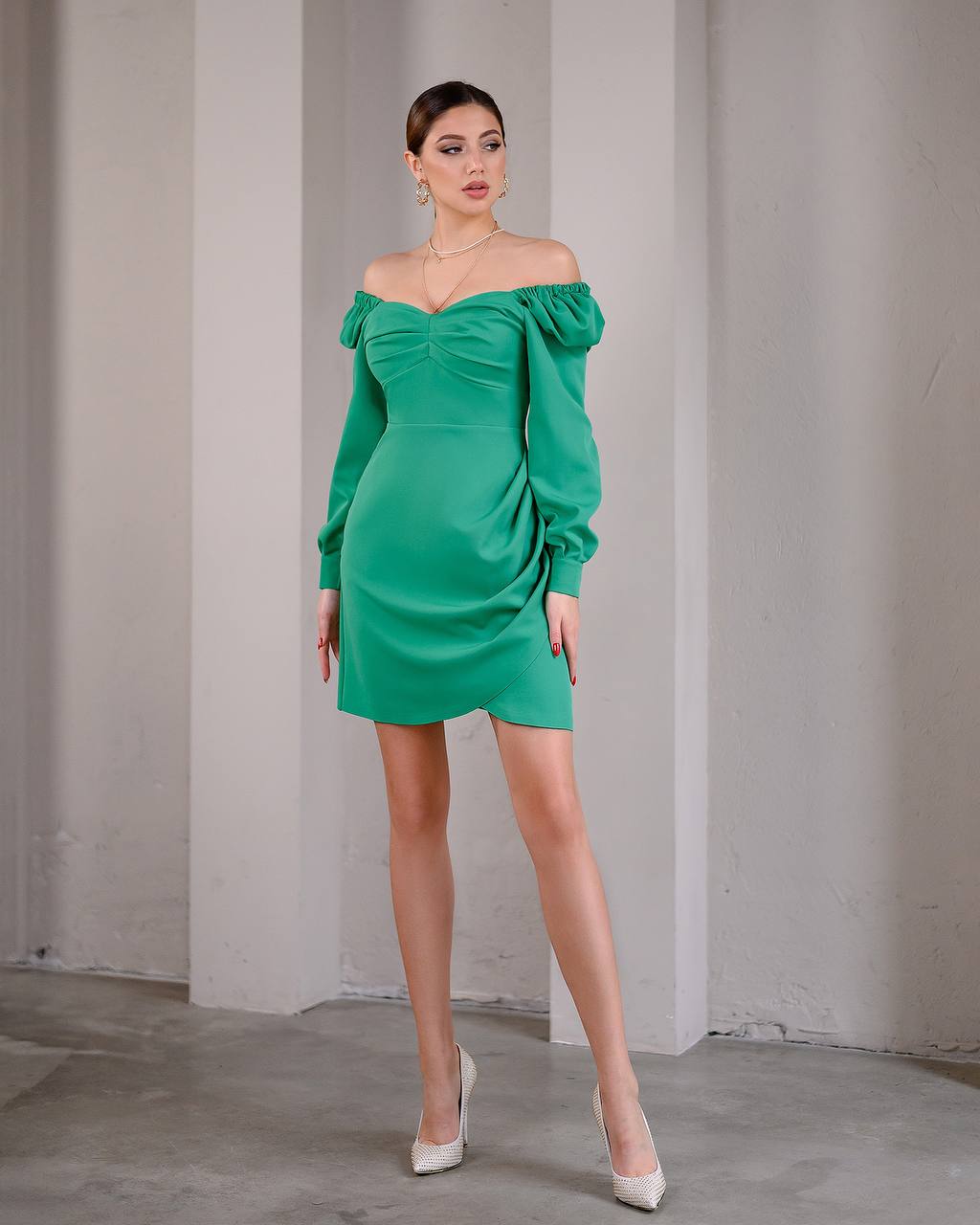 Woman wearing a green off-shoulder dress against a plain background