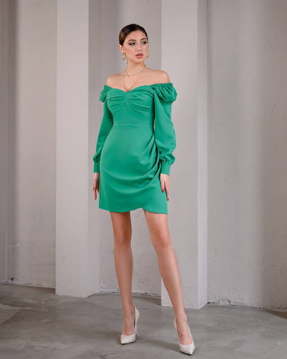 Woman wearing a green off-shoulder dress against a plain background