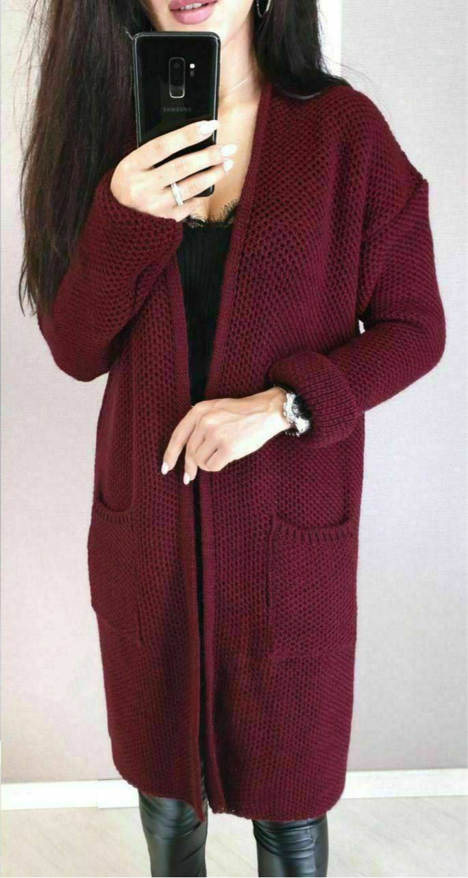 Person wearing a burgundy knitted cardigan against a plain background