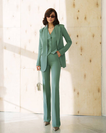 Woman wearing a green suit standing in a bright room with wooden walls.