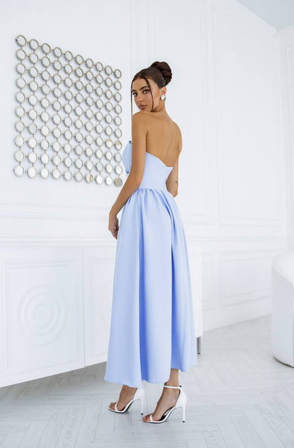 Woman wearing a light blue dress with cut-out design in a minimalistic room.