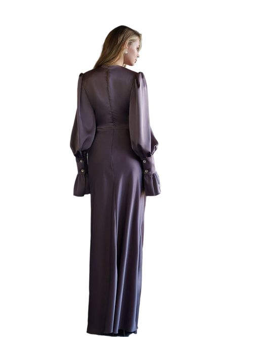 Woman wearing a long, dark purple dress with a fitted bodice and flowing skirt on a white background.