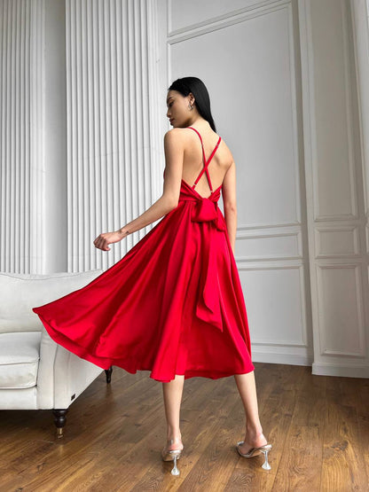 Woman in a red dress standing in a room with white walls and wooden floor.