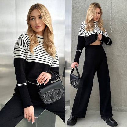 Woman in black and white striped sweater and black pants holding a black handbag.