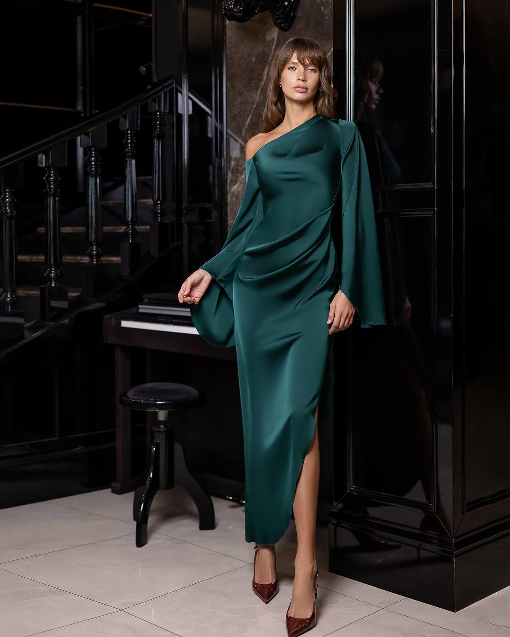 Woman in a teal dress standing in a room with a piano.