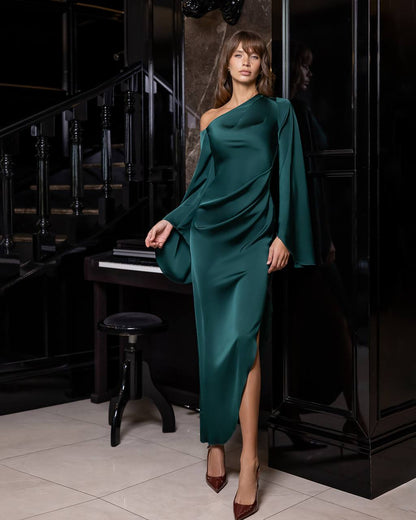 Woman in a teal dress standing in a room with a piano.
